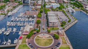 An aerial view of a marina with boats docked, a roundabout, and surrounding buildings. - Belmont King Studio - Walk Everywhere - Pet Friendly (Pensacola)