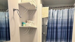 Kylpyhuone, jossa on valkoinen pesuallas, wc ja suihkuverho.