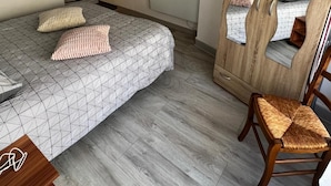A bedroom with a bed, a chair, a wardrobe, and a mirror. - Quiet and convenient apartment (Évaux-les-Bains)