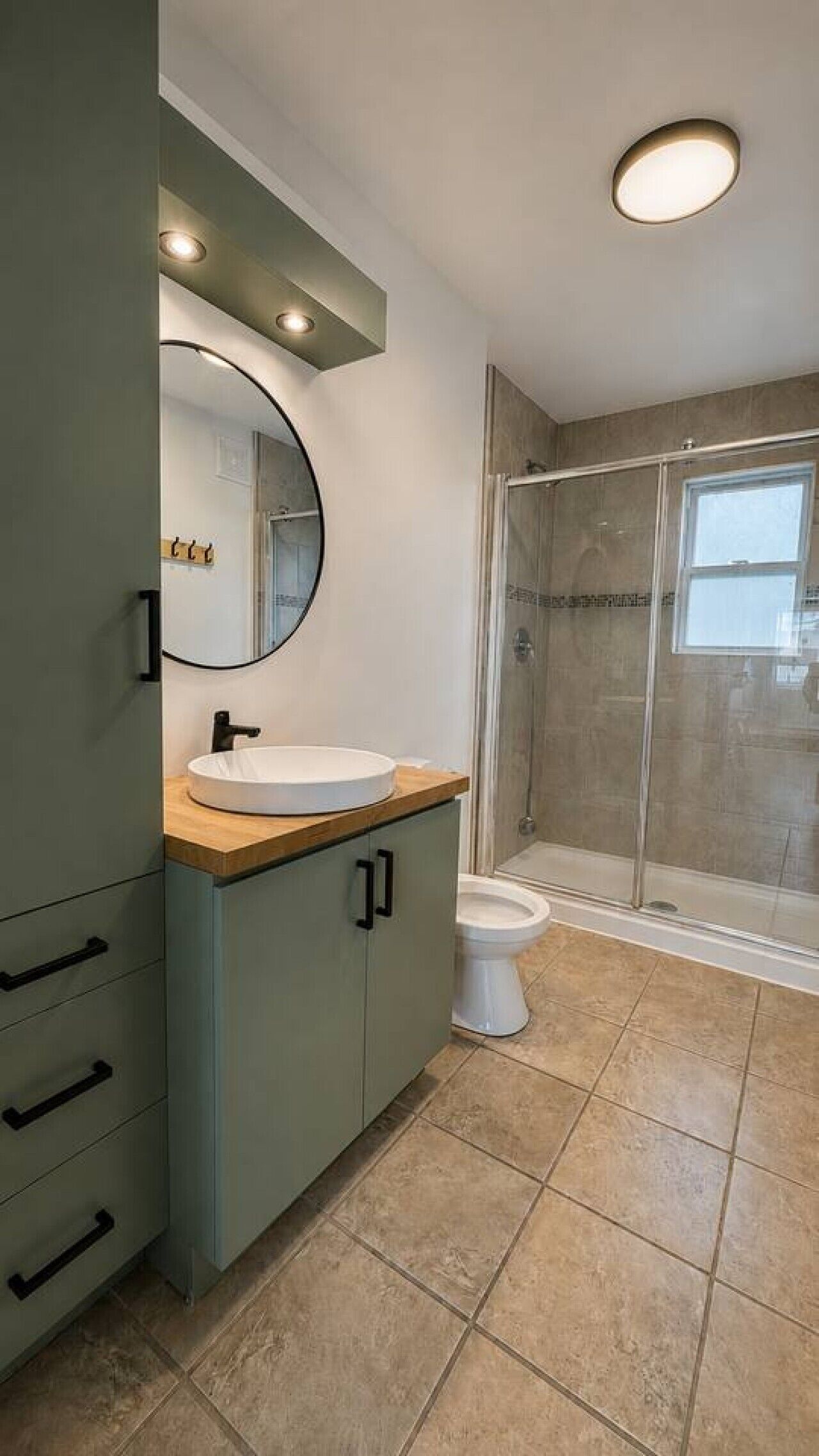 Un baño con lavabo, espejo, armario, inodoro y cabina de ducha con mampara de vidrio.