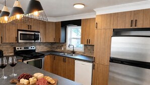 Une cuisine moderne avec des meubles en bois, des appareils électroménagers en acier inoxydable et des luminaires suspendus.