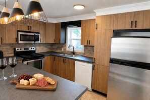 A modern kitchen with wooden cabinets, stainless steel appliances, and pendant lighting.