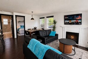 A living room with a fireplace, a dining area, and a TV displaying movie posters.