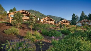 A row of wooden cabins with balconies, set on a hillside with a forest backdrop. - Leavenworth 2BR Mountain Villa – Full Kitchen, Balcony & Near Bavarian Village (Leavenworth)