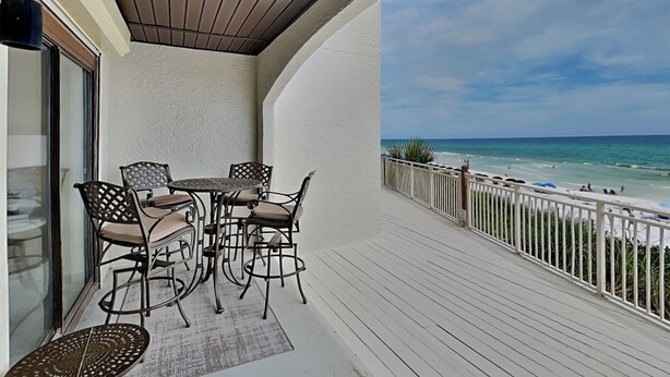 A balcony with a table and chairs, overlooking a beach with a clear sky. - Dune Villas #4A (Santa Rosa Beach)