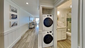 A laundry room with stacked washers and dryers, a shower, and a bathroom with a toilet and sink. - Dune Villas #4A (Santa Rosa Beach)