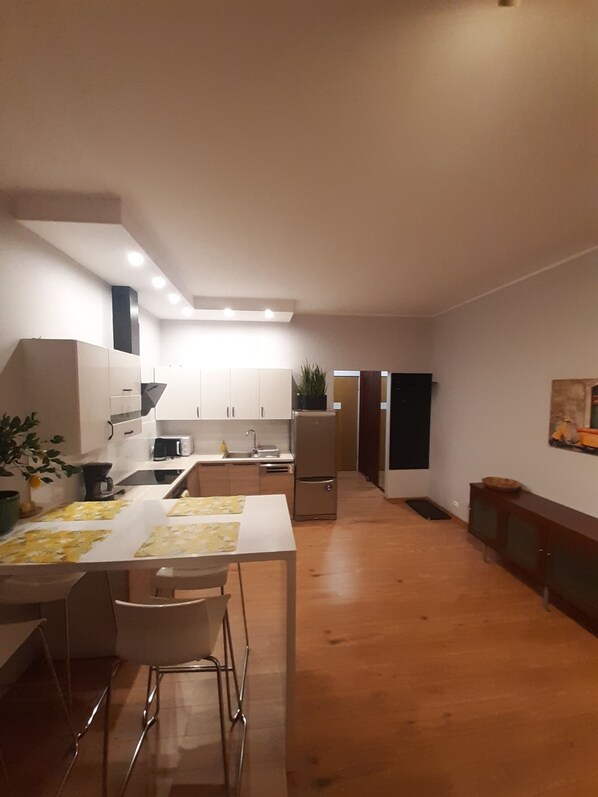 A modern kitchen with white cabinets, a dining table with chairs, a refrigerator, and a microwave.