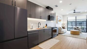 A modern kitchen with dark cabinetry, a stainless steel refrigerator, and a built-in microwave.