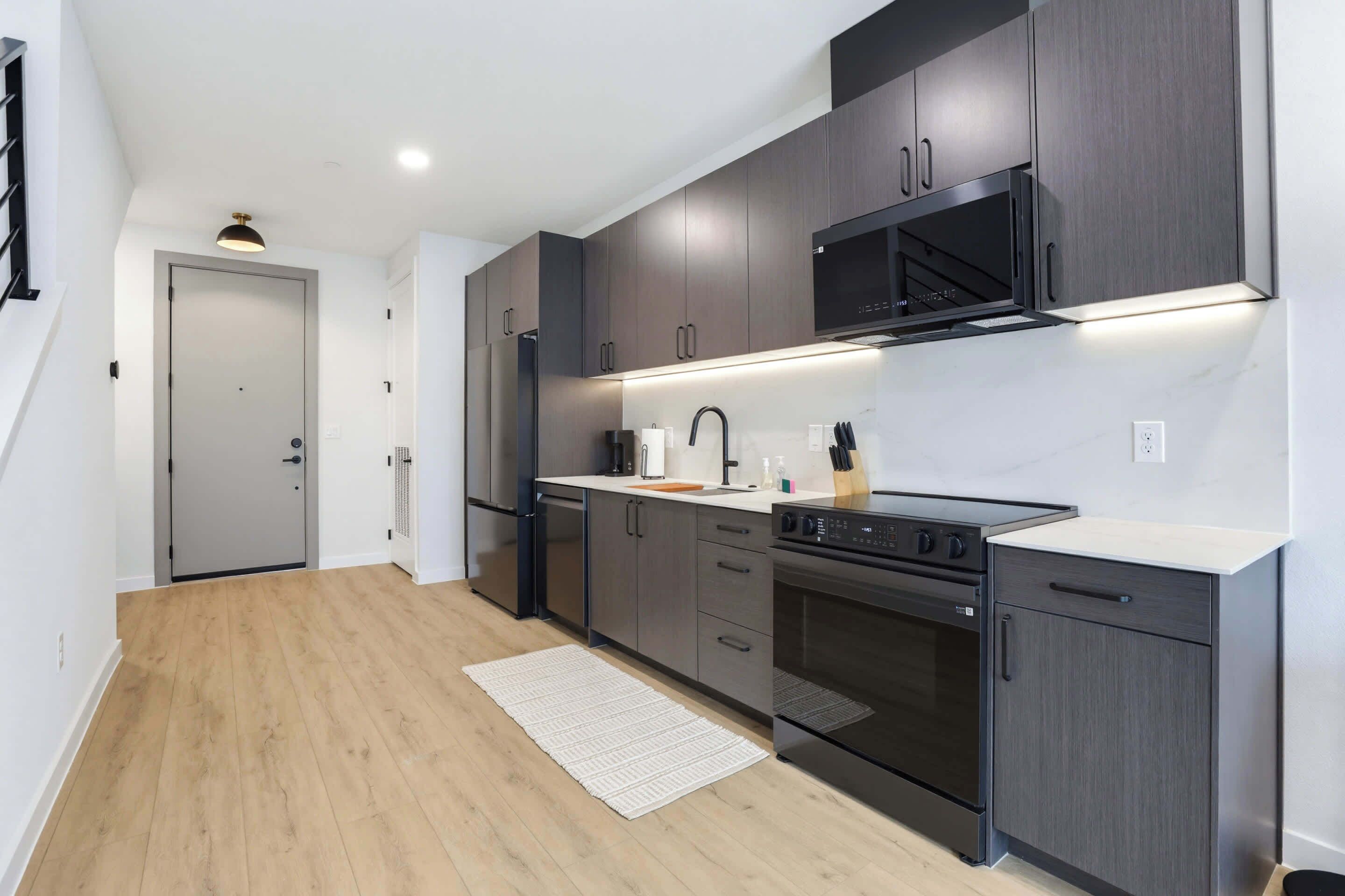 A modern kitchen with dark cabinets, a stainless steel range, and a built-in microwave.