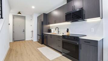 A modern kitchen with dark cabinets, a stainless steel range, and a built-in microwave.