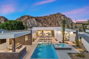 Ein modernes Haus mit Pool, Sitzgelegenheit im Freien und Blick auf felsige Berge.