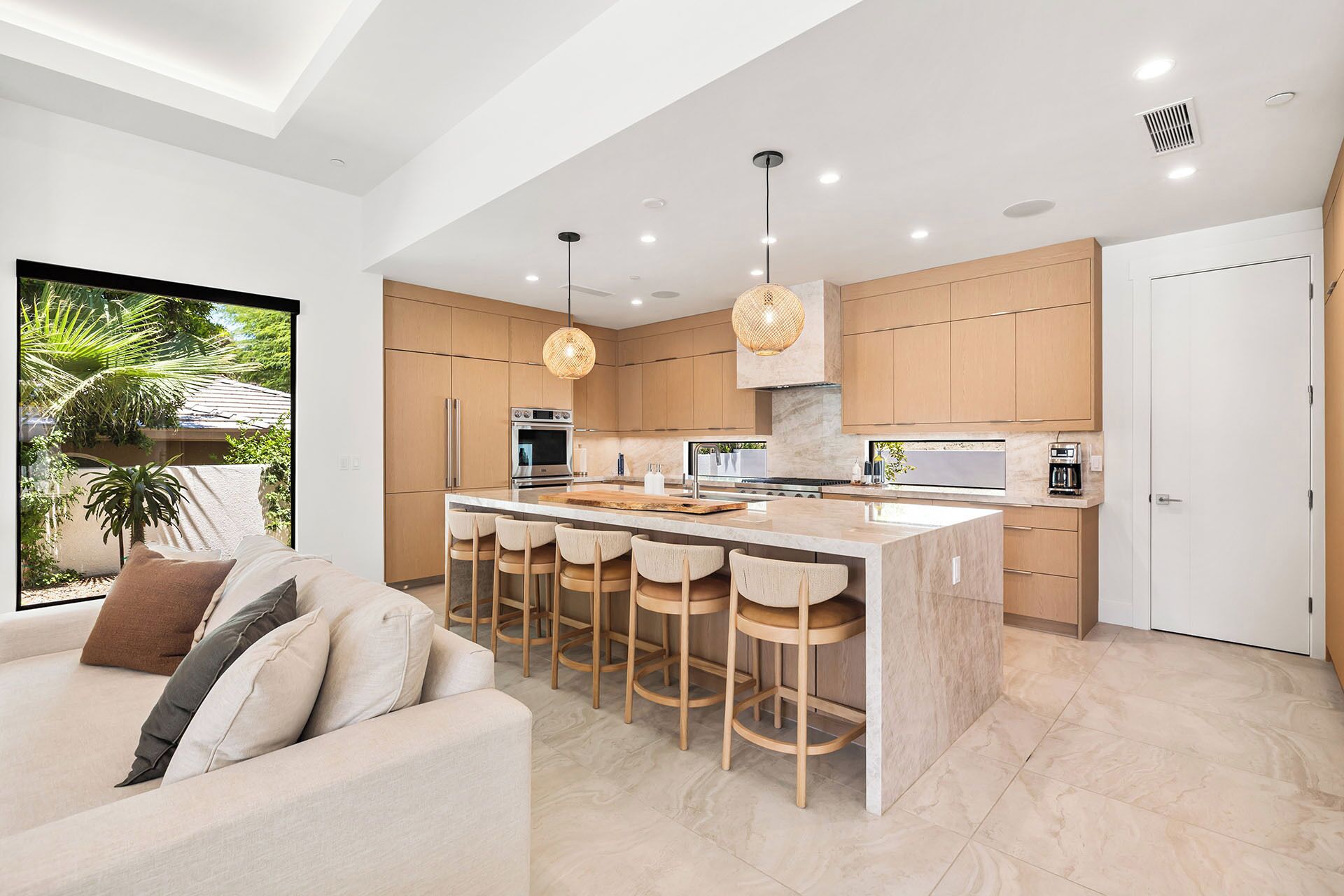 A modern kitchen with a central island, bar stools, and pendant lighting.
