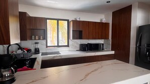 Een moderne keuken met marmeren werkbladen, houten keukenkastjes en een inbouwfornuis.