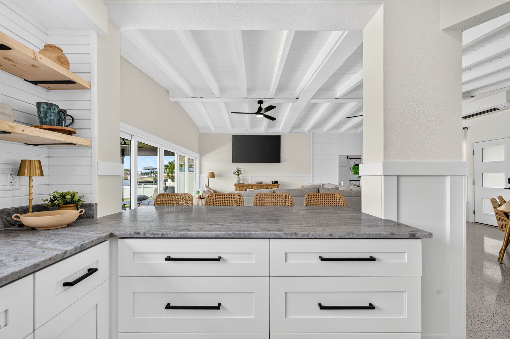Une cuisine moderne avec des meubles blancs, un plan de travail en granit et un ventilateur de plafond.