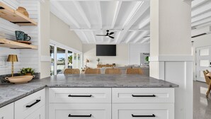 Eine moderne Küche mit weißen Schränken, einer Arbeitsplatte aus Granit und einem Deckenventilator.