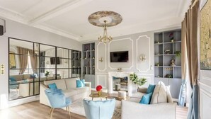 Ein Wohnzimmer mit einer Couch, Sesseln, einem Couchtisch, einem Fernseher und einem Kamin.