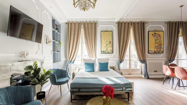 Ein geräumiges Hotelzimmer mit Bett, Sitzecke und an der Wand montiertem Fernseher.