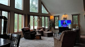 Ein geräumiges Wohnzimmer mit großen Fenstern, einem Flachbildfernseher und bequemen Sitzmöglichkeiten.