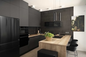 Eine moderne Küche mit dunklen Schränken, einer Holztheke und einem schwarzen Kühlschrank.
