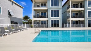 A modern multi-story building with a swimming pool, outdoor seating, and balconies. - Dixie Tide - Hammock Dunes West (Orange Beach)