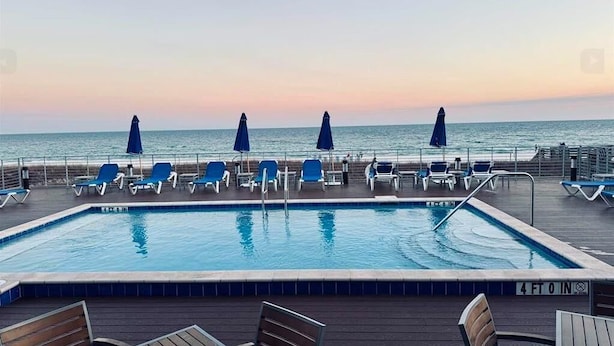 Area piscina con lettini e ombrelloni, vista sull'oceano.