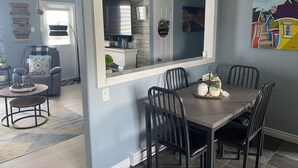 A dining area with a large mirror, a clock, and a view into the kitchen.