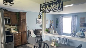 A kitchen with wooden cabinets, a built-in microwave, and a dining area with a table and chairs.