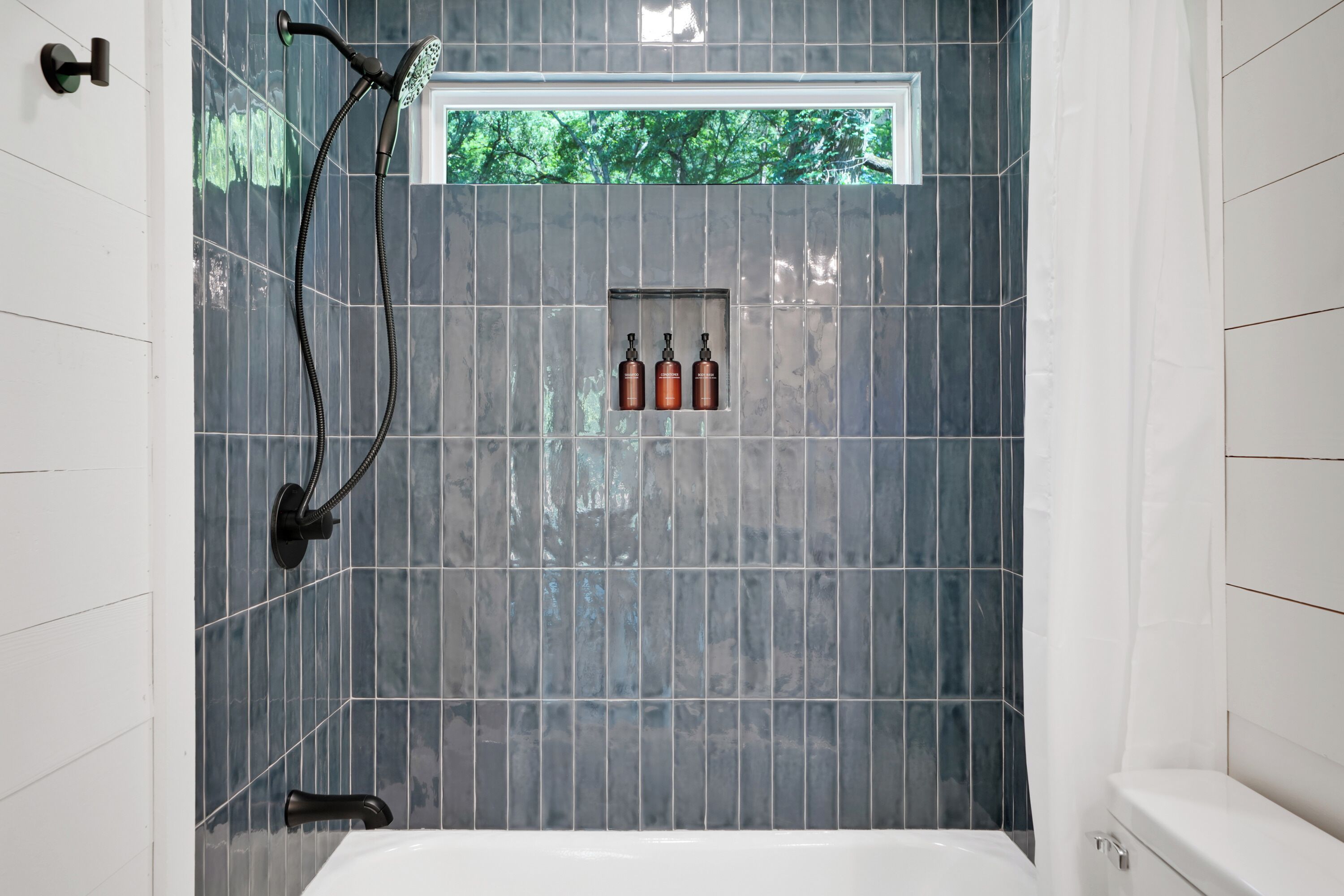 Baño con ducha, ventana y artículos de aseo.