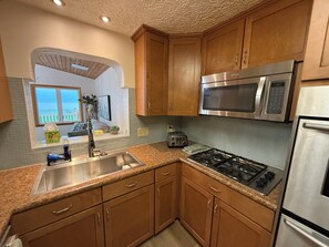 A kitchen with wooden cabinets, a stainless steel sink, a gas stove, a microwave, and a toaster. - Spacious Lakeview Retreat Built for Relaxation & Longer Stays (Lorain)