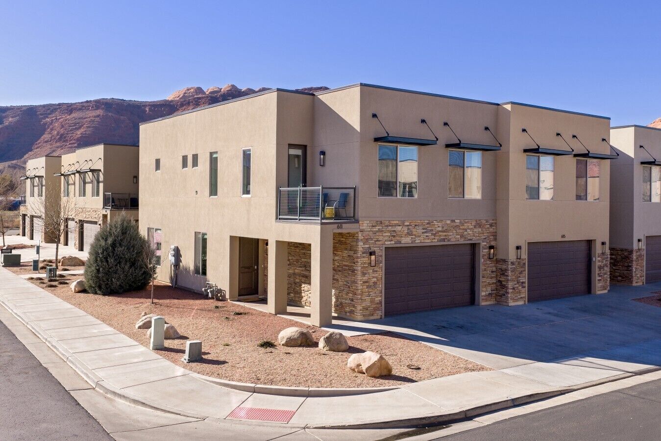 A modern multi-story residential building with a flat roof, large windows, and a stone facade.