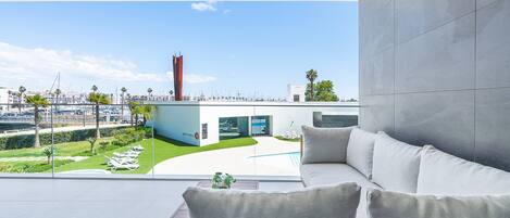 A modern interior with a view of a marina, a white sofa, and a glass wall.