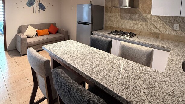 Eine moderne Küche mit Granitarbeitsplatte, Edelstahlgeräten und einer Essecke mit Barhocker.