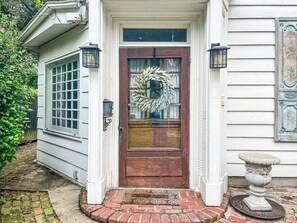 A front door with a wreath, a doormat, and a lantern on either side.
