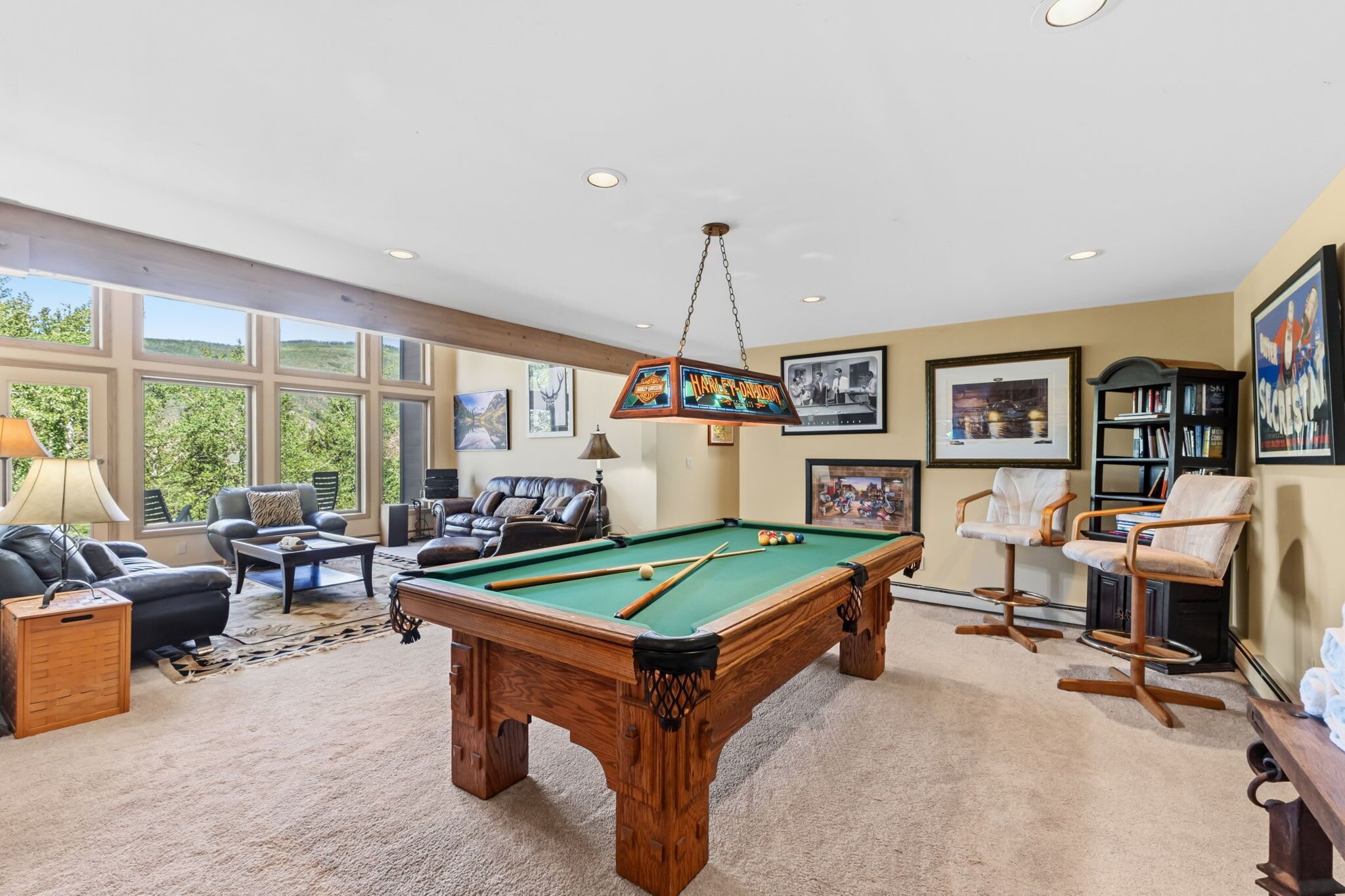 A pool table in a room with a sofa, chairs, and framed pictures on the walls.