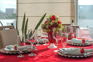 A table set with clear glassware, white plates, and a red tablecloth. - Luxury Penthouse in Jurerê Internacional: 150m² Terrace, Private Pool and Suite (Florianópolis)