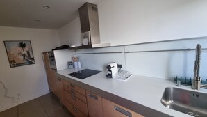 Een moderne keuken met een roestvrijstalen spoelbak, een ingebouwde oven en een koffieapparaat.