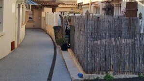 Een smalle straat met gebouwen aan beide kanten, een houten hek en een heldere blauwe lucht.