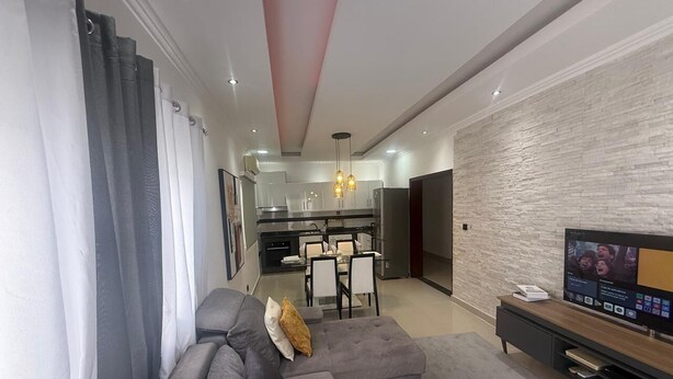 A modern living room with a grey sofa, a small round table, and a flat-screen TV.