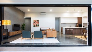 Una sala de estar moderna con sofá, sillones, televisión y lámpara.