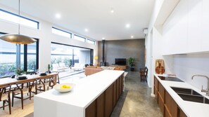Cocina moderna con una isla central, comedor con sillas de madera y un ventanal que proporciona luz natural.