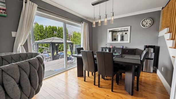 A modern kitchen with a dining area, large windows, and a view of the outdoors. - Cozy 3-bedroom house in charming Mercier with AC (Mercier)