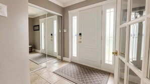 A hallway with a double door, a mirror, a patterned rug, and a tiled floor. - Cozy 3-bedroom house in charming Mercier with AC (Mercier)