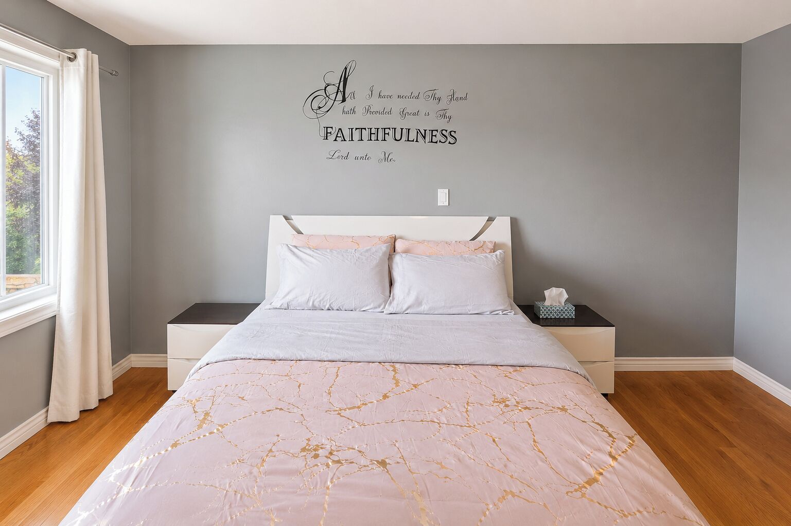 Een slaapkamer met een bed, nachtkastje, wanddecoratie en een raam.