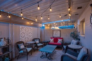 Eine Terrasse im Freien mit Korbmöbeln, einem roten Sofa und Lichterketten.
