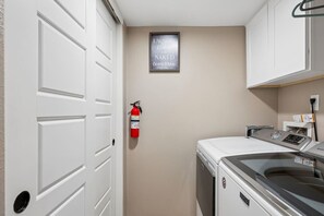 A laundry room with a fire extinguisher, a wall-mounted sign, and a washing machine. - Old Town Scottsdale - Pool - Grill - Sun Loungers (Scottsdale)