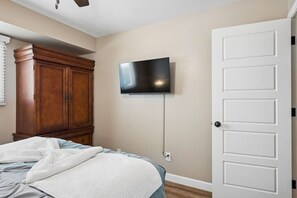 A bedroom with a bed, a wooden wardrobe, a television mounted on the wall, and a white door. - Old Town Scottsdale - Pool - Grill - Sun Loungers (Scottsdale)