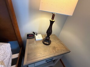 A bedside table with a lamp, a digital clock, and a power strip. - Private apartment suite in Omaha! (Omaha)