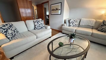 A living room with two sofas, a glass coffee table, and a framed picture on the wall.