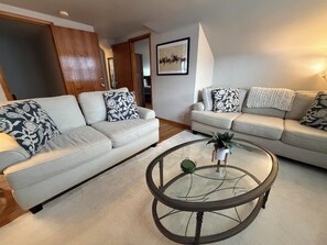 A living room with two sofas, a glass coffee table, and a framed picture on the wall. - Private apartment suite in Omaha! (Omaha)