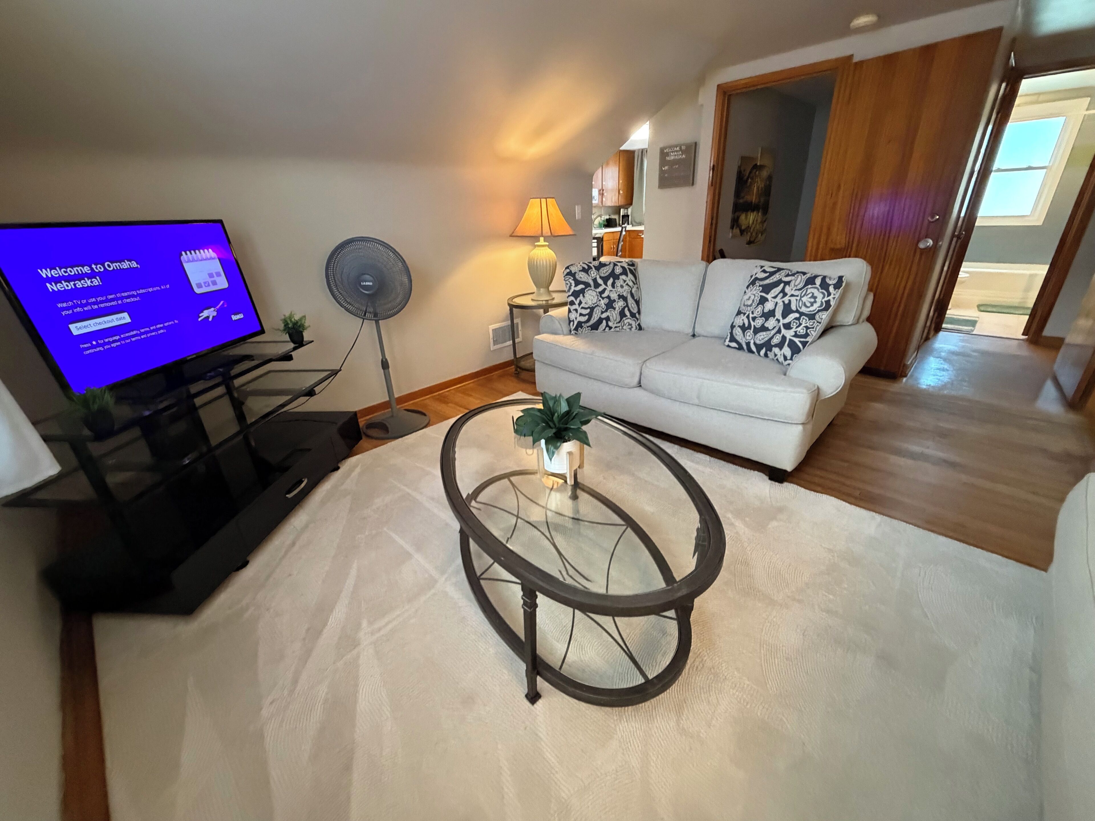 Un salon comprenant un canapé, une table basse, un téléviseur, un ventilateur et une lampe.
